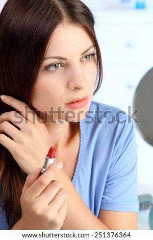 young woman holding a lipstick in her hand