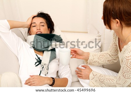 sick woman lying on the couch, next to her is sitting her good friend