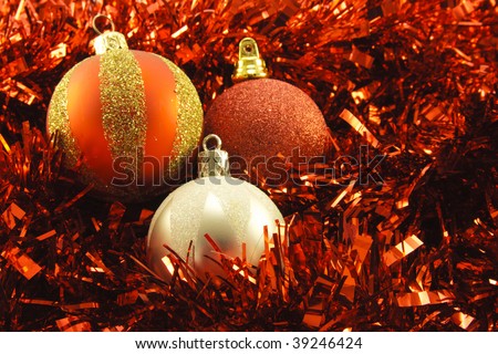 Shiny single silver round bauble and two red round baubles on red tinsel background