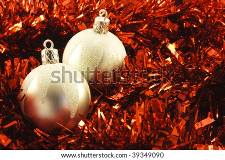 Two shiny silver round baubles on red tinsel background