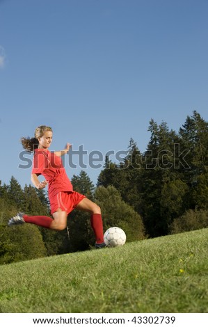 Girl Kicks soccer ball on a field