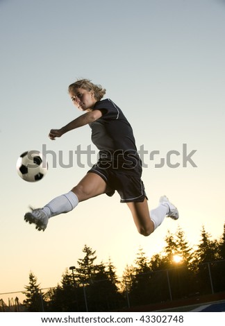 Girl Kicks soccer ball in mid air in the early morning