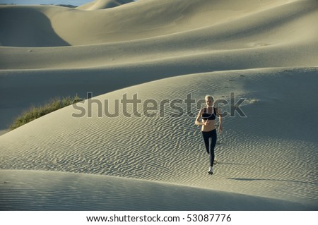 Woman runs on sand dunes.