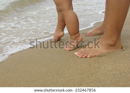 Baby feet walking and mother foot on the beach
