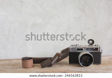 Old film camera and a roll of film on wood