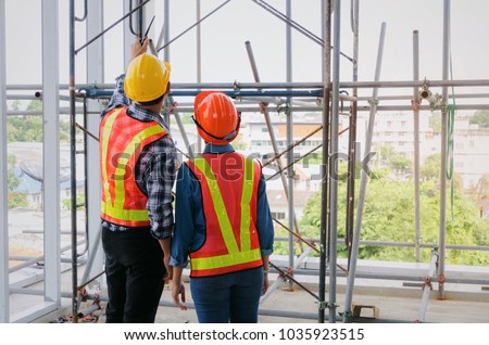 couple of engineer or technician man and woman with safety helmet holding mobile radio phone planning about building plan to greeting start up project in construction site building, industry concept