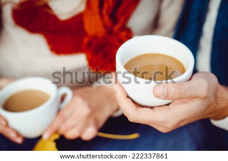 Two hands are holding two hot cups of tea