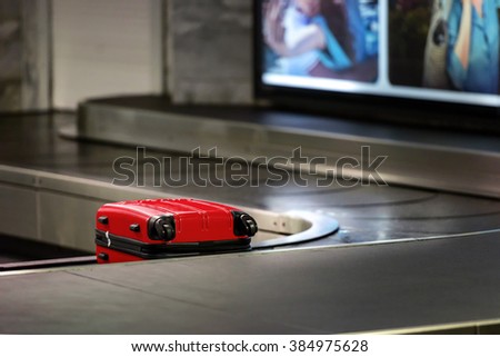 Red suitcase waiting be picked up on a conveyor belt