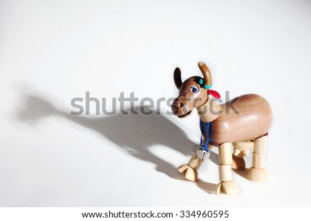Wooden toy cow with articulated parts on white background with shadow