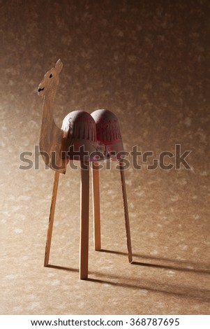 A scrap camel made of reused materials on a brown background with a dramatic light.