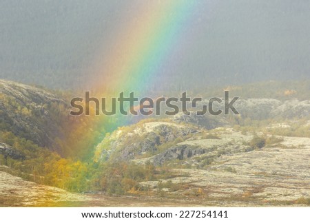 Rainbow over arctic rocky plateau covered with lichens and mosses