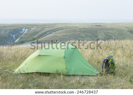 Green solo tourist tent and a backpack set up in chalk steppe of Rovenki, Belgorod region in southern Russia