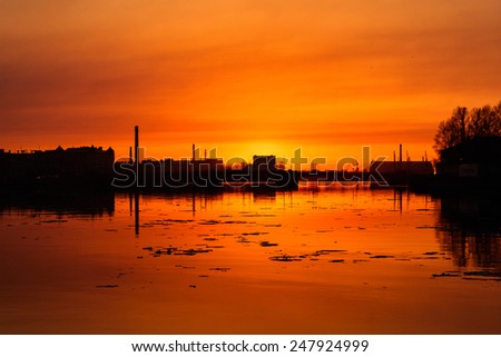 Industrial part of Saint Petersburg silhouette reflected in Neva river at spring evening sunset