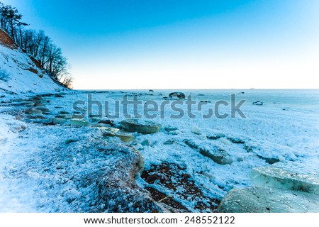Sea shore with rocks and ice blocks after snow storm on Gulf of Finland, Russia