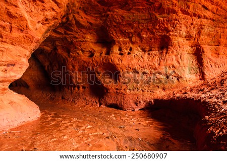 Red sandstone cave with water stream on its bottom, near Vyra village in Russian North-west