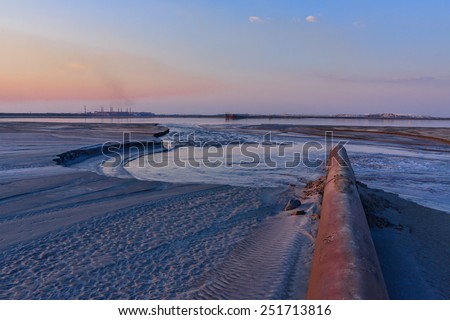 Rusty pipe polluting man-made desert in periphery of Kursk Magnetic Anomaly iron mine in Belgorod region, southern Russia