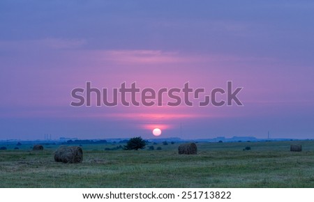 Sun rising above protected area of Yamskaya Steppe with stacks of harvested hay, Belgorod region in southern Russia