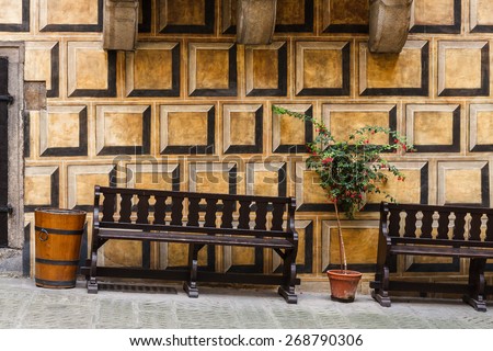 Bench and tree in a pot in front of a painted wall in Cesky Krumlov Castle inner yard