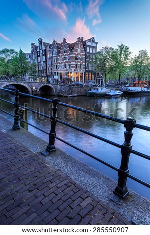 Typical late evening view of deep blue sky and canal houses behind a bridge in Haarlemmerbuurt district of Amsterdam, Netherlands