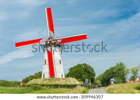 Traditional Holland windmill with red wings in Damme, small village near Bruges, Belgium