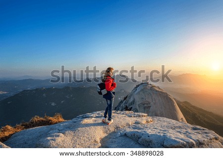 Woman stands on the peak of stone in Bukhansan national park,Seoul in South Korea and watching to Sunrise. Beautiful moment the miracle of nature.