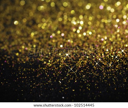 Gold glitter on black background with selective focus