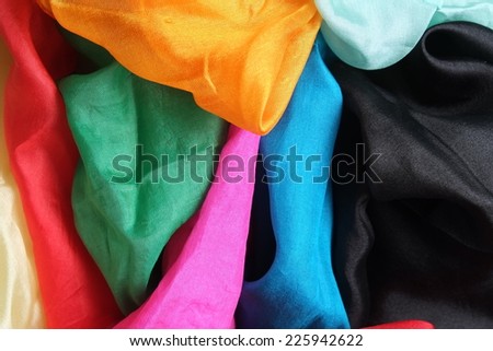 A colorful mixture of several shiny silk handkerchiefs. Red, blue, aqua blue, black, yellow, orange, pink, fuchsia, golden, green