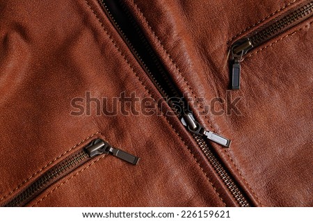 Main zipper and front pockets zippers of a brown leather biker jacket. Nylon seams detail
