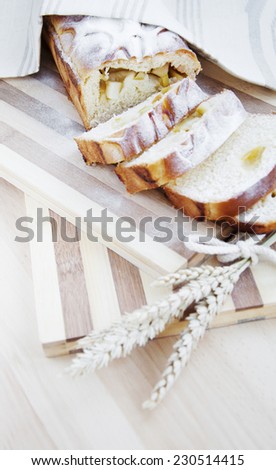 Bread stuffed with apple and wheat on wooden background