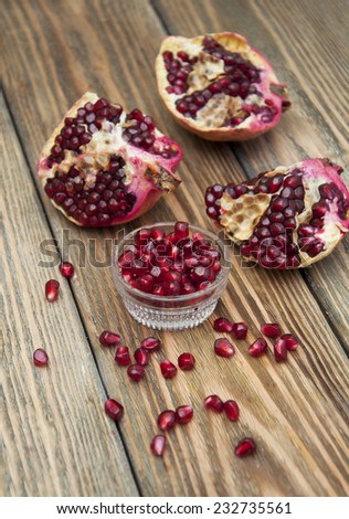 Piece of ripe pomegranate and red grains on wooden table
