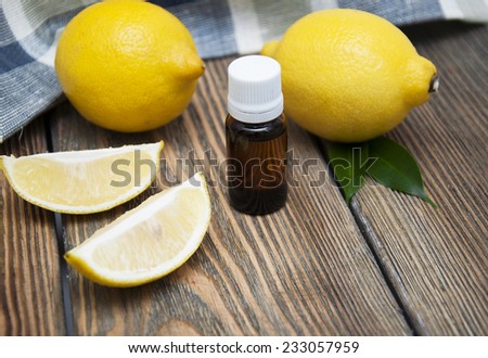 Bottle of essensial lemon oil with fresh organic fruit on a wooden background