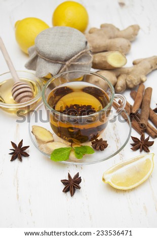 A cup of tea with fresh honey, lemon,ginger and spices on wooden background