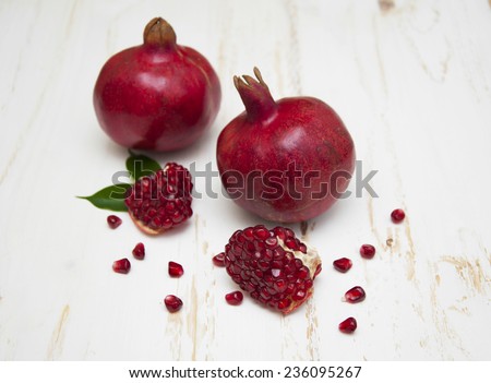 Juicy pomegranate and red grains on a white wooden background