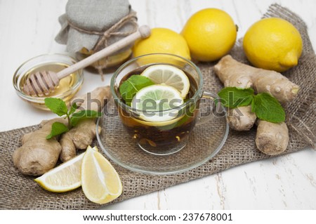 A cup of tea with fresh honey, lemon, ginger on wooden background