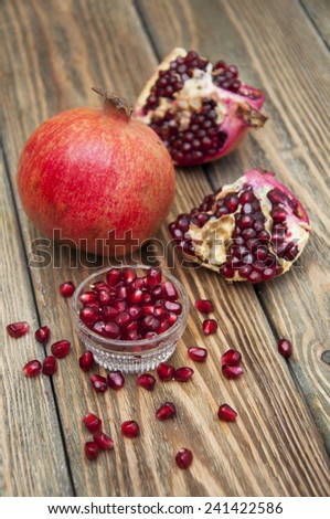 Juicy pomegranate and red grains on wooden background