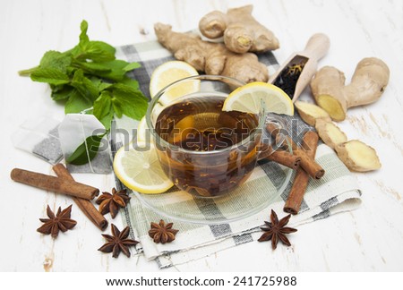 A cup of tea with fresh lemon, ginger and spices on wooden background