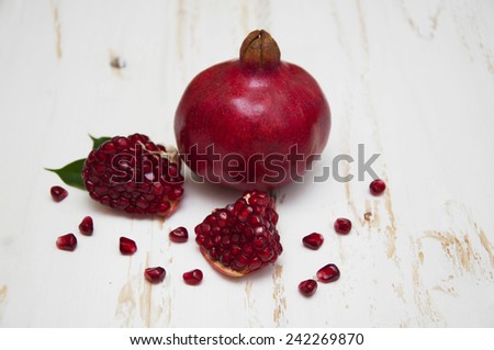 Juicy pomegranate and red grains on a white wooden background