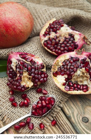 Piece of ripe pomegranate and red grains on wooden table