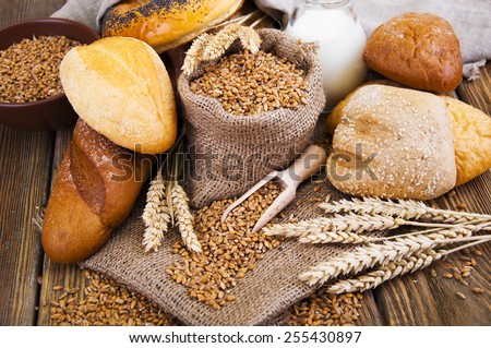 Different bread, wheat and milk on a wooden table