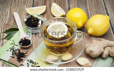A cup of tea with fresh honey, lemon, ginger on wooden background