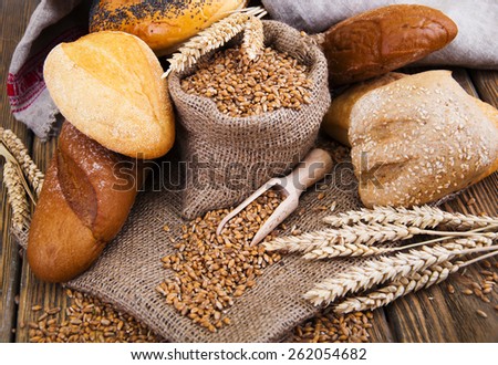 Different bread with wheat in a small bag , on a wooden background