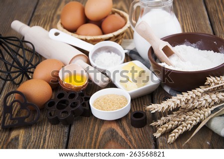 Baking ingredients - eggs, flour,milk,sugar and butter on a wooden background