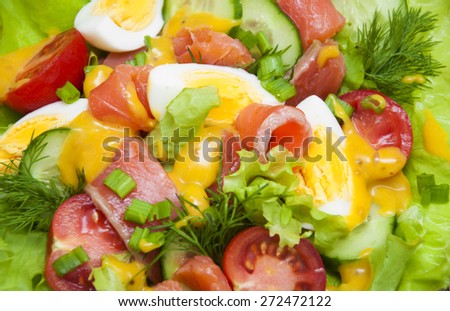 Mixed salad with slices of salmon and honey - mustard sauce on a wooden background.Food - background