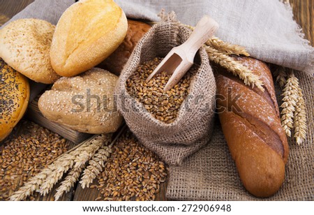 Different bread with wheat in a small bag on a wooden background
