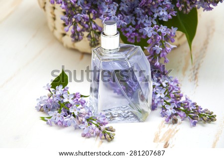 Common lilac perfume with a bouquet of lilac on white wooden background