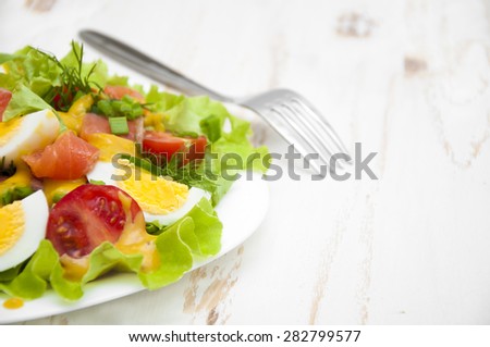 Mixed salad with slices of salmon and honey - mustard sauce on a wooden background
