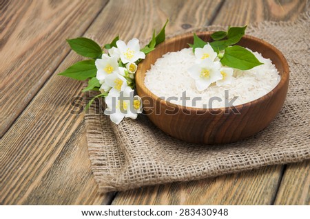 Wooden plate with jasmine rice and jasmine flowers on a wooden background