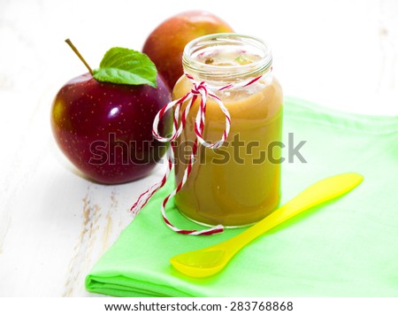 Baby apple puree in a jar with apples on wooden white background
