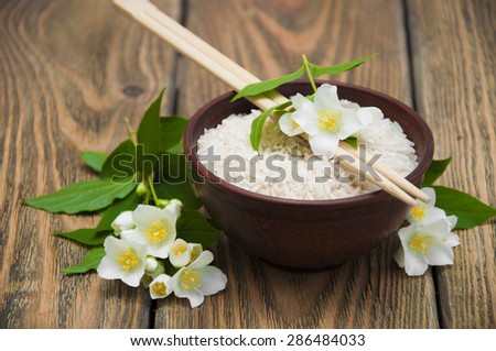 Plate with jasmine rice and jasmine flowers on a wooden background