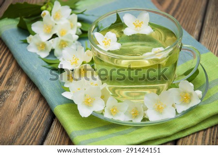 A cup of jasmine tea with jasmine flowers on a wooden background
